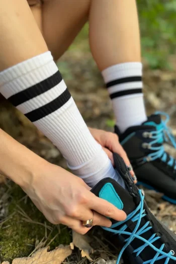 Osoba nosząca białe skarpetki z czarnymi paskami, które są wykonane z wełny merino .
