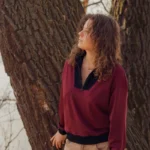 Klasyczna bluza z wysokiej jakości wełny merino, bordowa z kontrastowym czarnym wykończeniem przy szyi.