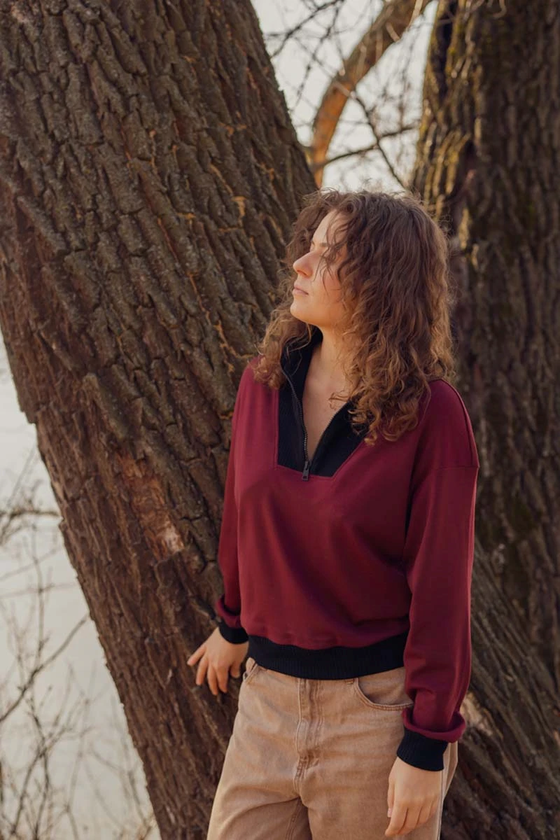 Klasyczna bluza z wysokiej jakości wełny merino, bordowa z kontrastowym czarnym wykończeniem przy szyi.