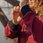 Minimalistyczna bluza w głębokim bordowym odcieniu, wykonana z wełny merino, z czarnym kołnierzem dla kontrastu.