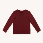 Koszulka dziecięca z długim rękawem z wełny merino w kolorze bordowym. Przód koszulki