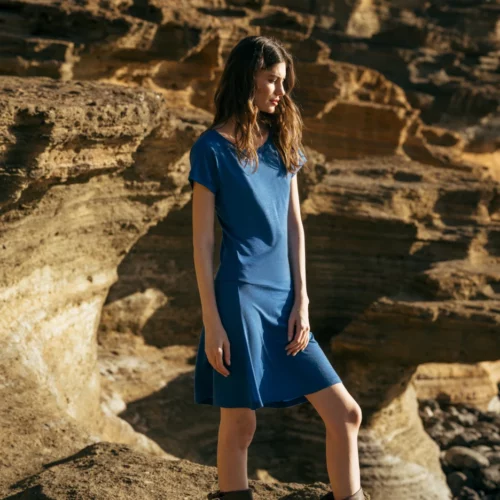 Kobieta w Spódnicy z wełny merino marszczona szara panterka stoi na skalistym terenie z warstwowymi kamiennymi klifami oświetlonymi światłem słonecznym.