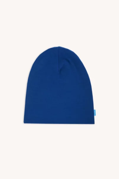Zwykła czapka beanie w kolorze królewskiego błękitu jest ułożona płasko na jasnym tle, z małą niebieską metką po prawej stronie.