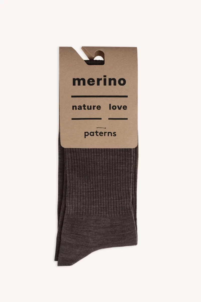 Męska koszulka z wełny merynosów w kolorze mokka z kartonową metką z napisem "merino, nature love, paters" jest starannie złożona, częściowo widoczna pod metką.