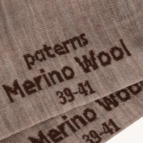 Zbliżenie na koszulkę mokka z wełny merino męski, pokazujące jasnobrązowy materiał z napisem "Patents Merino Wool 39-41" w kolorze ciemnobrązowym.