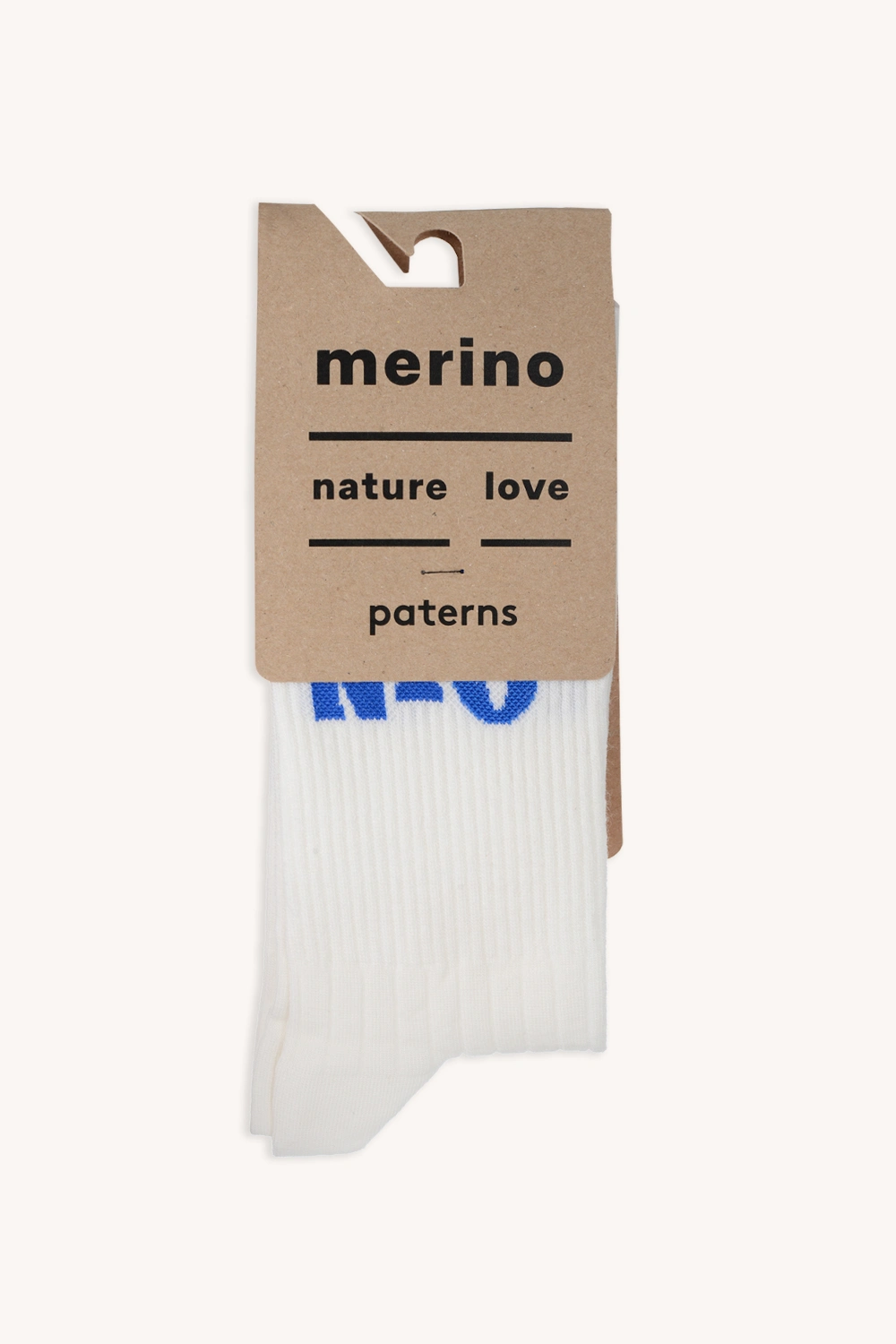 Para białych Skarpety trekkingowe merino z napisem RÓB NIC w kolorze czarnym, zapakowane na brązowym kartonie z napisem "nature love patterns". Niebieskie litery są częściowo widoczne na skarpetach.