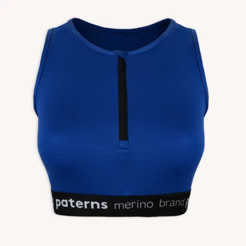 Kobaltowo-niebieski top bez rękawów z krótkim krojem, z czarnym zamkiem błyskawicznym z przodu i elastyczną wstawką z napisem „paters merino” w kolorze białym, z kolekcji „Zestaw sportowy z wełny merino do biegania kobalt”.