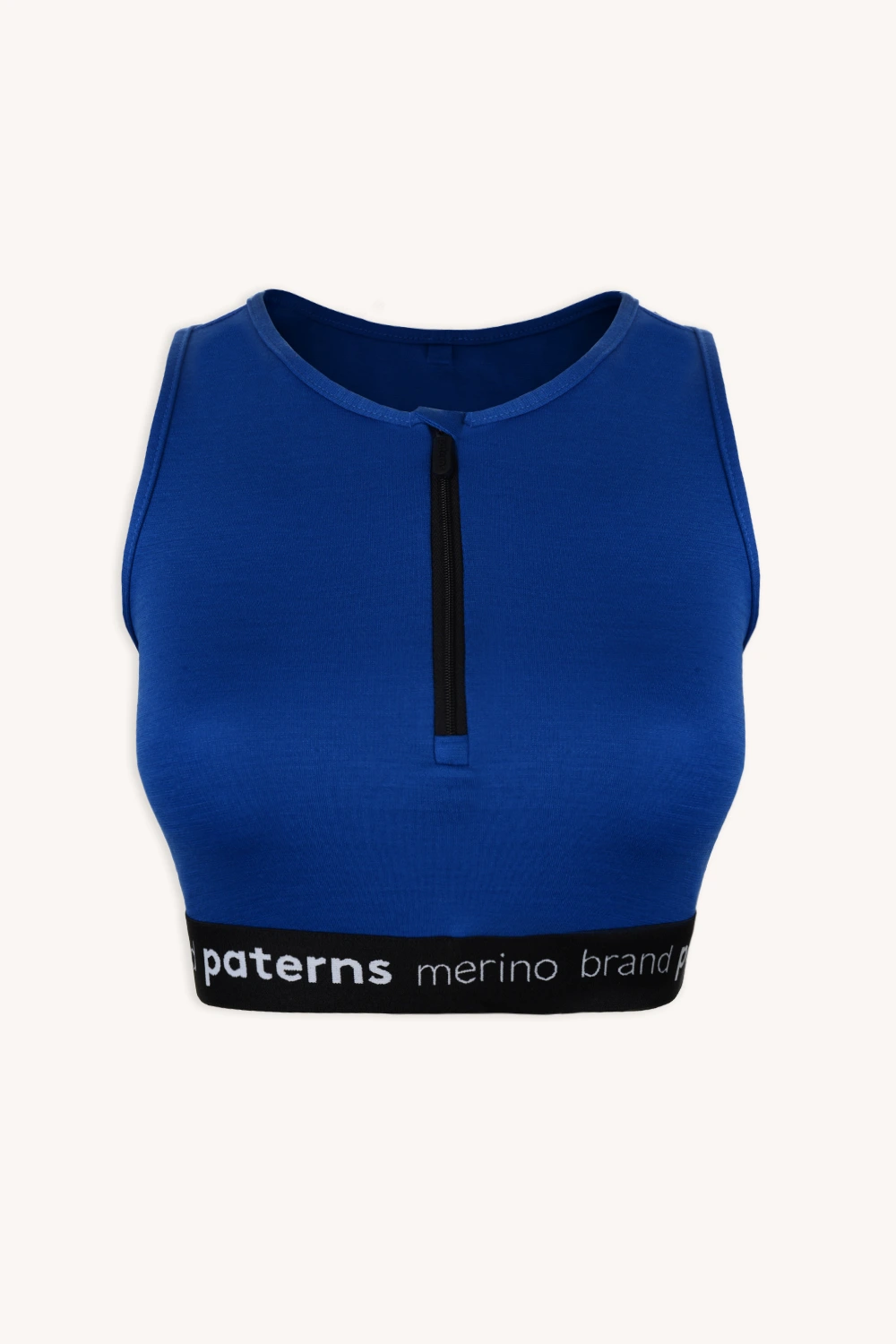 Kobaltowo-niebieski top bez rękawów z krótkim krojem, z czarnym zamkiem błyskawicznym z przodu i elastyczną wstawką z napisem „paters merino” w kolorze białym, z kolekcji „Zestaw sportowy z wełny merino do biegania kobalt”.