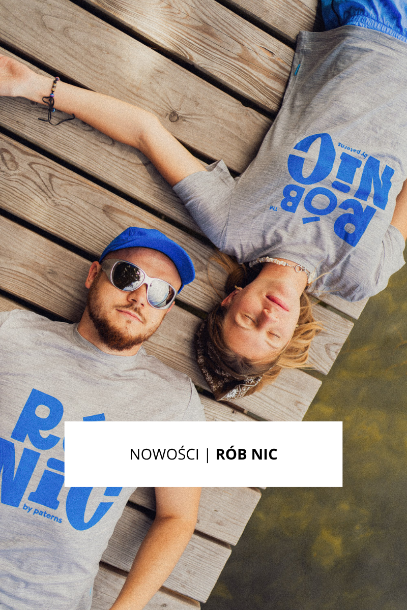 Dwie osoby leżą na drewnianych deskach nad wodą; obie mają na sobie szare koszulki z dużym niebieskim napisem „RÓB NIC”. Jedna z nich ma na sobie okulary przeciwsłoneczne i niebieską czapkę, a druga – bandanę i naszyjnik.